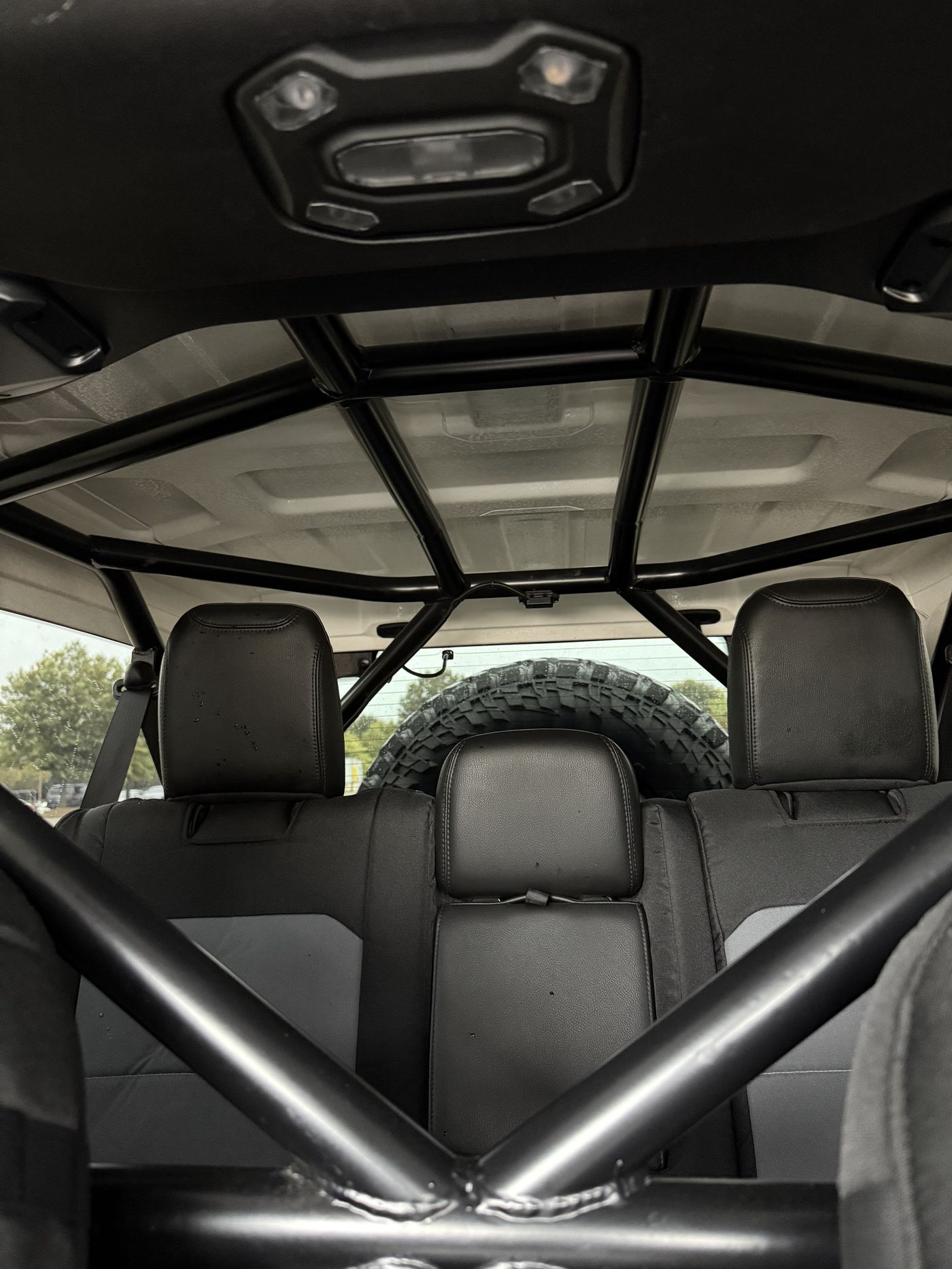 Rock Solid Fab roll cage seen from the rear seats with spare tire visible through the rear window